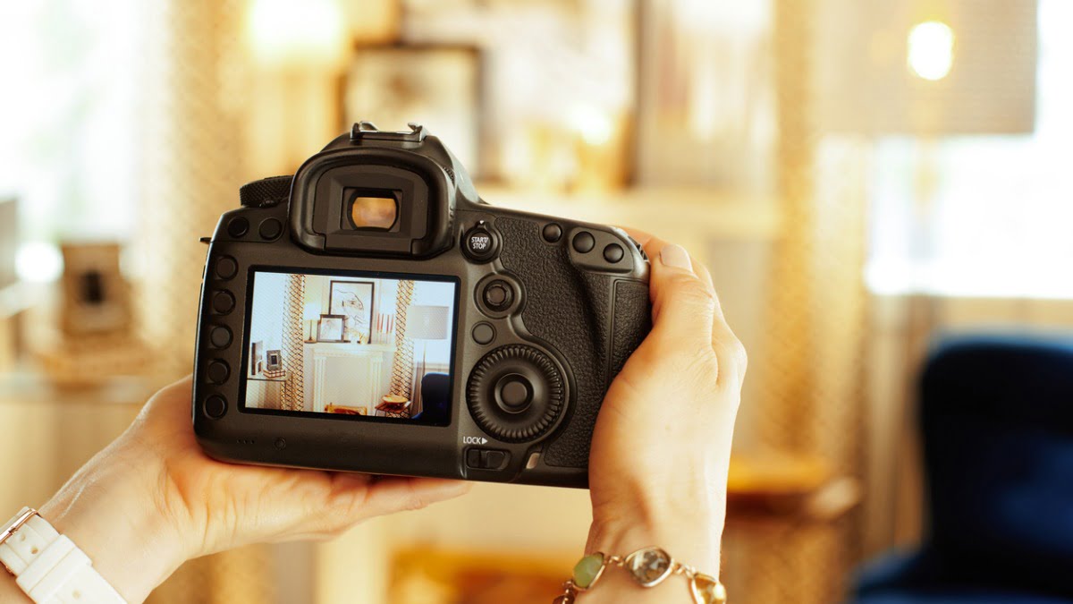 hands holding a camera taking a photo of a living room