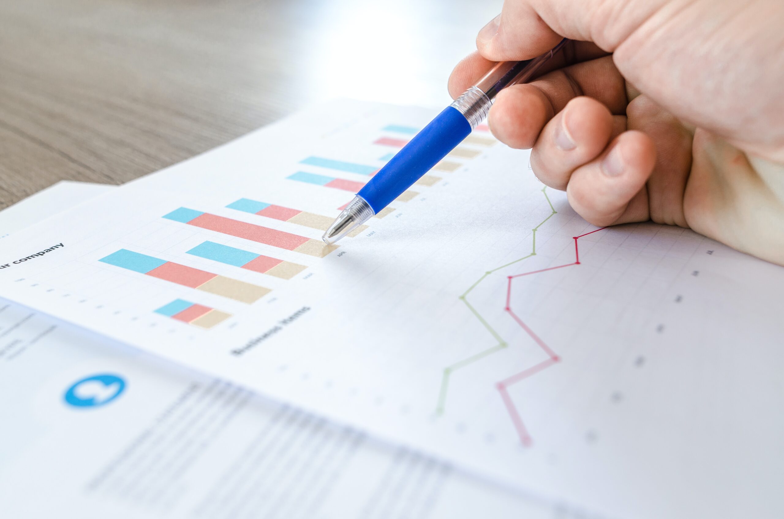 hand with pen pointed at a paper with graphs