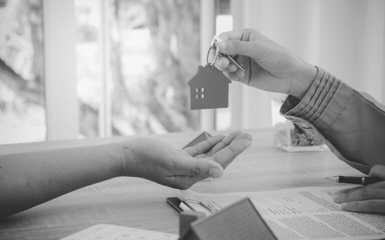 Key with house-shaped keychain being handed to a new tenant
