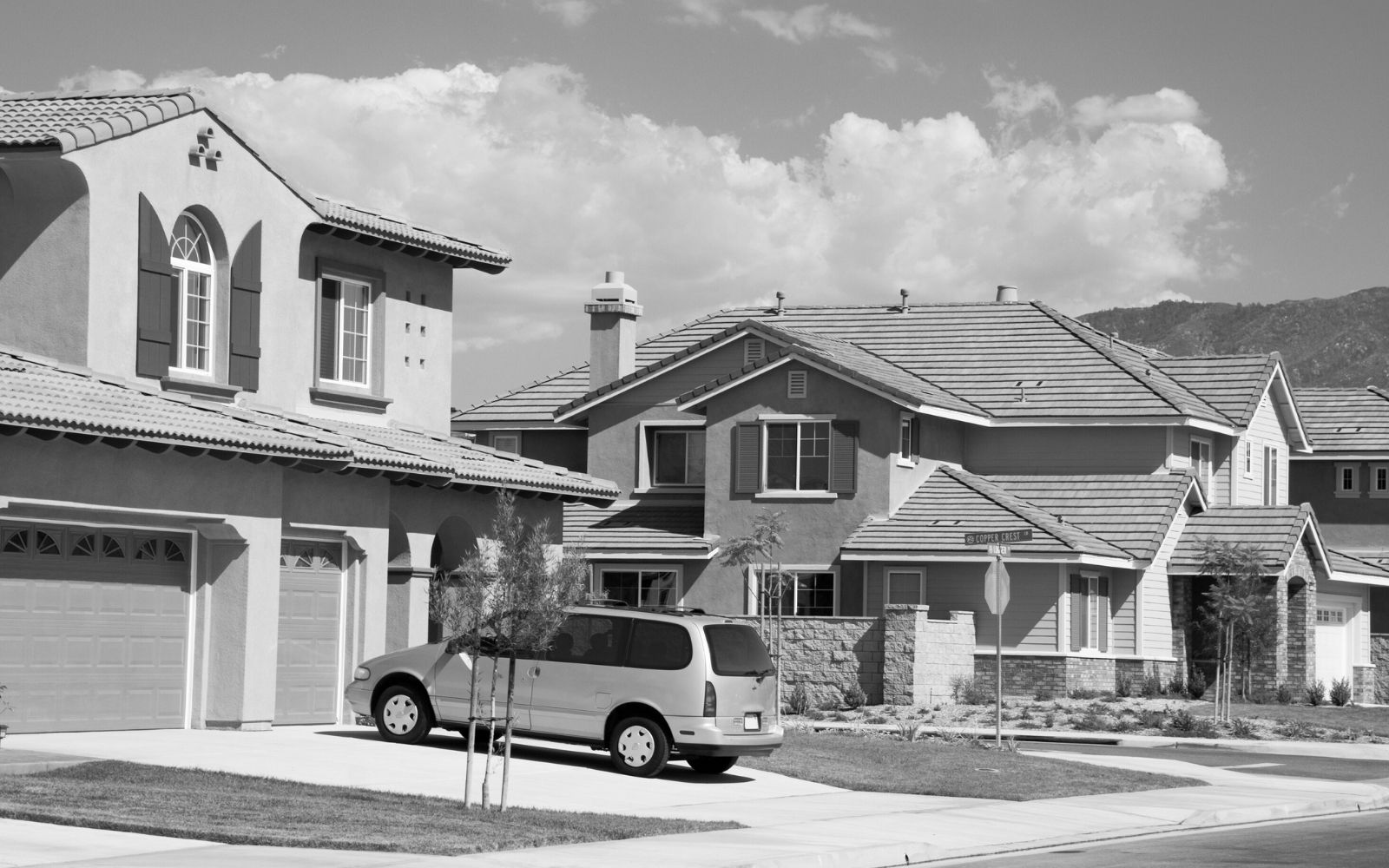 : Suburban residential street with multiple houses and a minivan parked in driveway