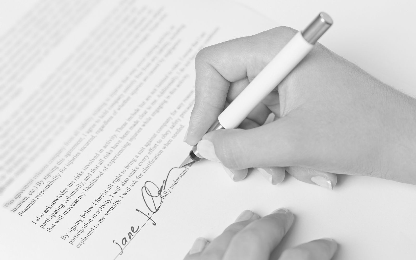 Hand signing rental lease document with black ink pen