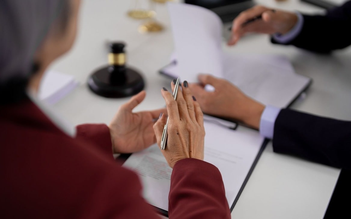 Close-up of two people signing rental agreement documents in an office setting.