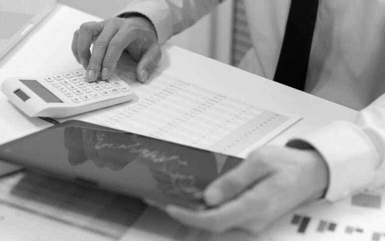 Businessperson using a calculator and reviewing financial charts on a desk during an economic recession
