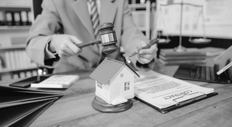 Judge striking gavel beside a small house model on a legal desk, symbolizing real estate and antitrust court rulings in the United States.